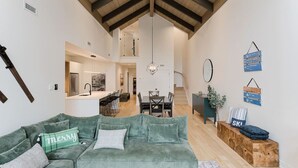 Ein geräumiger Wohnbereich mit einem grünen Sofa, einem Esstisch und einer Treppe, die in eine obere Ebene führt.