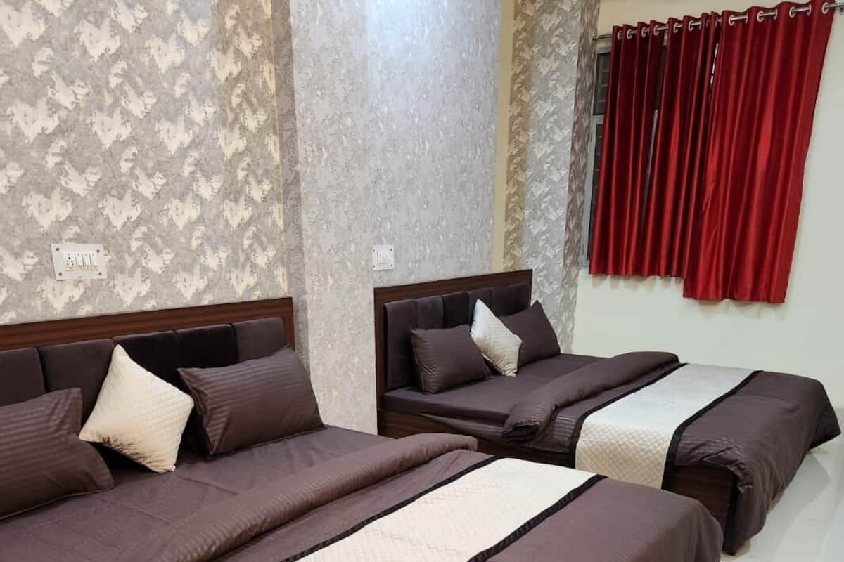 Habitación de hotel con tres camas, cada una con cabecero y varios almohadones.