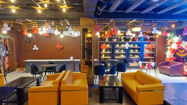 A modern lounge area with yellow sofas, a bar counter, and a variety of seating options. - Syrus Hotel  (Mathura)