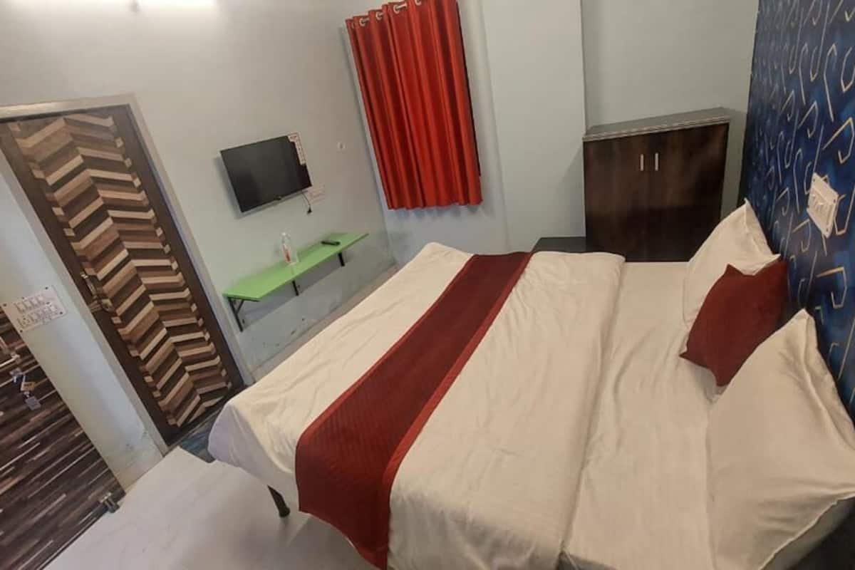 Habitación de hotel con cama, televisión, escritorio y armario.