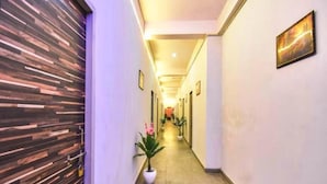 A hallway with a modern design, featuring a wooden panel wall on the left and a series of framed pictures on the right. - Syrus Hotel  (Mathura)