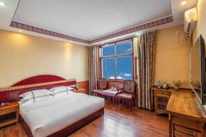 Una habitación de hotel con una cama grande, un escritorio, una silla, un televisor y una ventana con cortinas.
