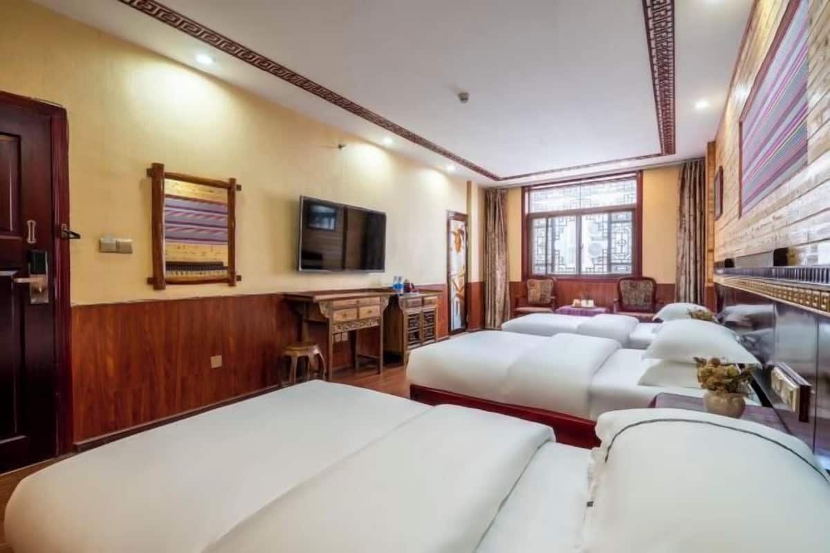 Une chambre d’hôtel avec deux lits, un bureau, une télévision et une fenêtre avec des rideaux.