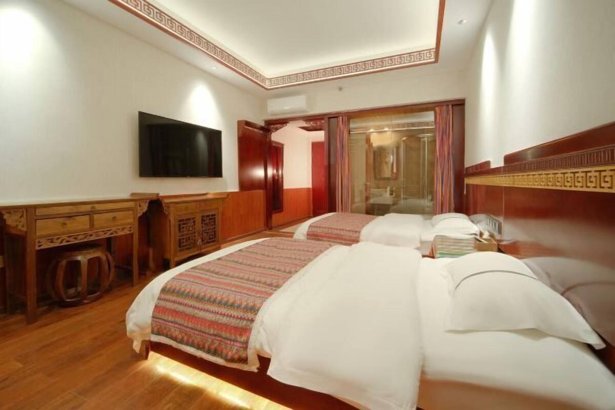 Une chambre d’hôtel avec deux lits, une télévision et une commode en bois.