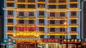 Um edifício de vários andares com varandas, letreiros iluminados e elementos arquitetônicos tradicionais.