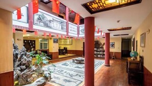 Um hall amplo com um jardim de pedras central, piso de madeira e decoração tradicional.