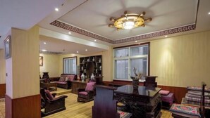 Quarto tradicional com piso de madeira, uma mesa central e vários espaços de estar.