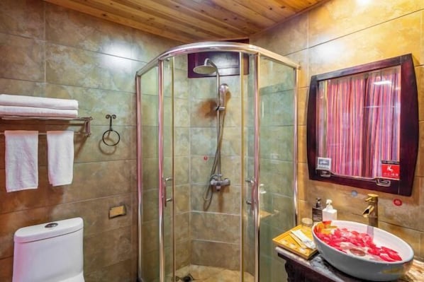 A bathroom with a glass-enclosed shower, a white toilet, a sink with a basin, and a mirror with a curtain.