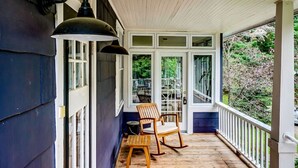 En inglasad veranda med trägolv, två gungstolar och ett bord.