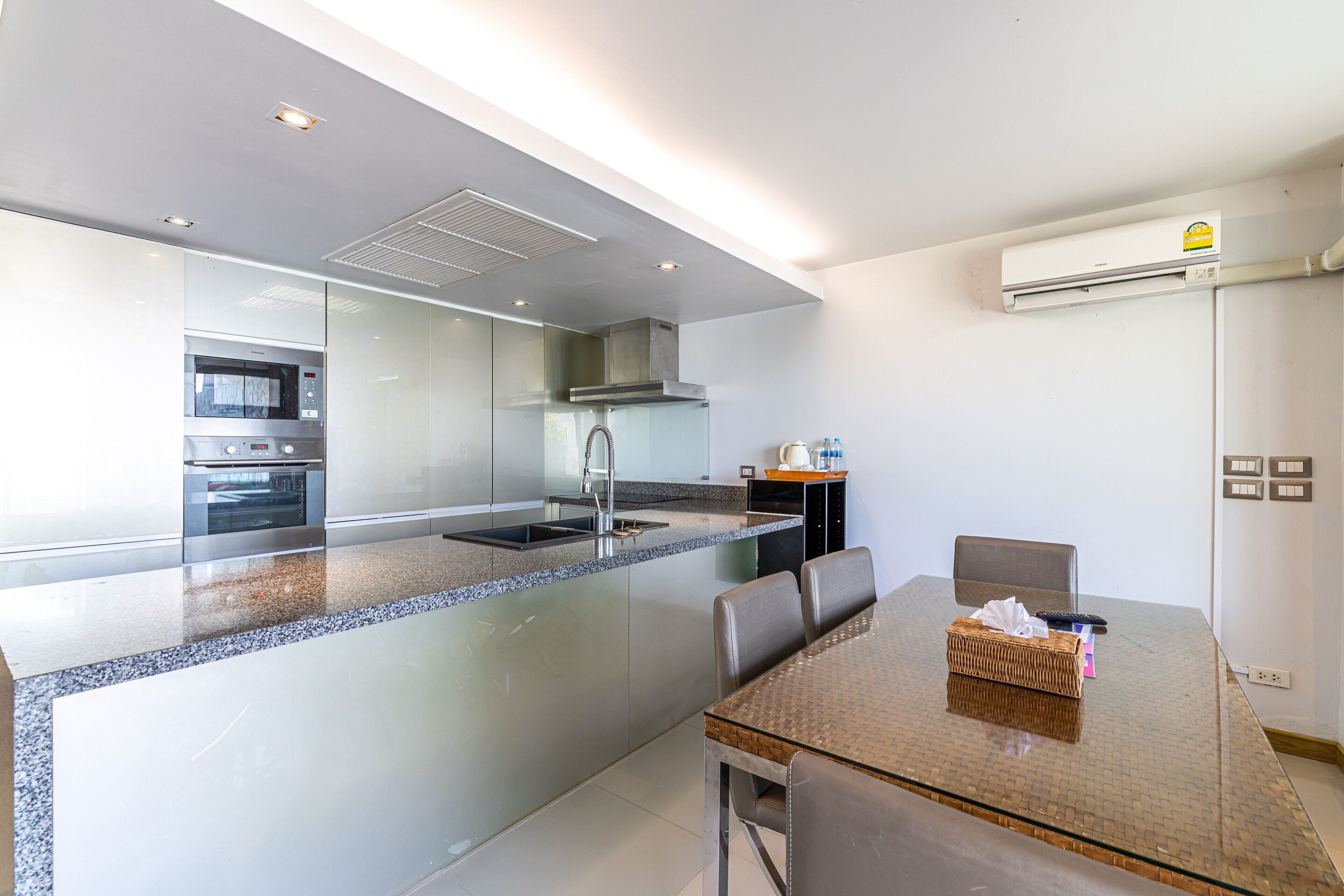 A modern kitchen with a central island, built-in oven, and stainless steel appliances.
