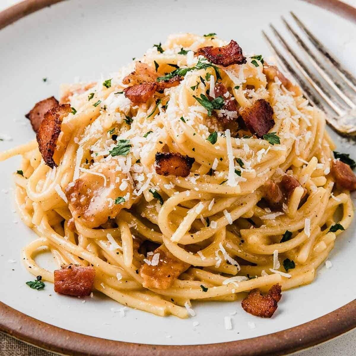 A plate of spaghetti with bacon and cheese.