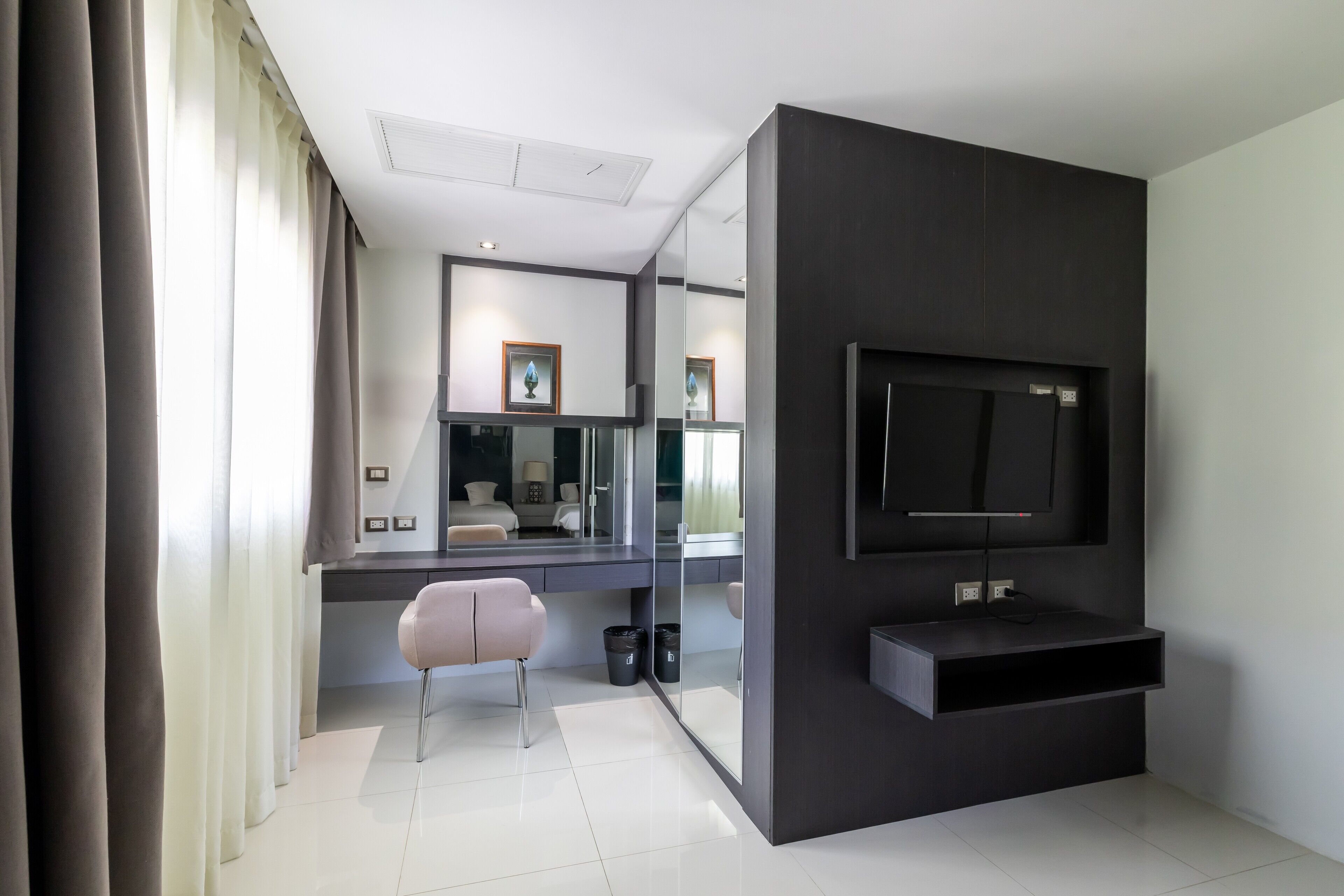 A modern bedroom with a large TV, a glass partition, a desk, and a chair.