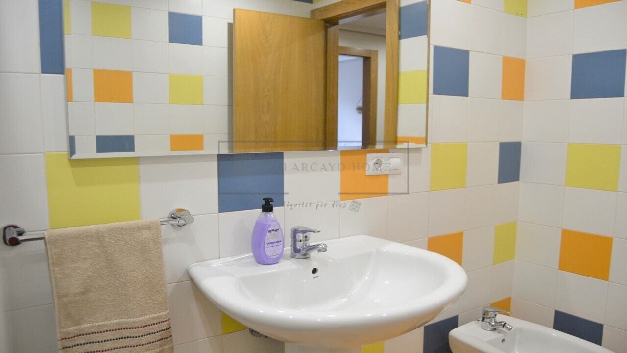 Une salle de bain avec un lavabo blanc, un miroir et un meuble en bois.