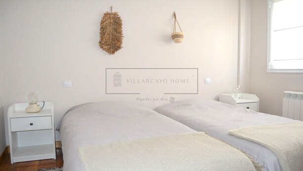 A bedroom with two beds, a nightstand with a lamp, a wall-mounted basket, and a window. - VILLARCAYO HOME  3-habitaciones, lujoso apartamento muy amplio y céntrico (VILLARCAYO)