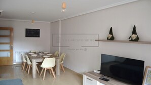 A modern living room with a dining area, a flat-screen TV, and decorative gnome figures on a shelf. - VILLARCAYO HOME  3-habitaciones, lujoso apartamento muy amplio y céntrico (VILLARCAYO)