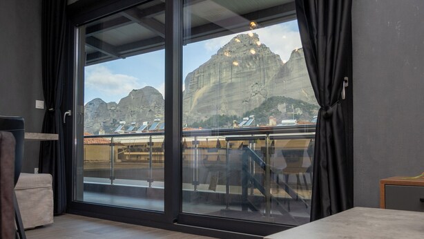 Una habitación moderna con un gran ventanal corredera que da a un balcón con vistas a la montaña.