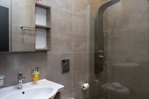 Une salle de bain moderne avec une douche à parois de verre, un lavabo avec un robinet chromé et un miroir au-dessus du lavabo.