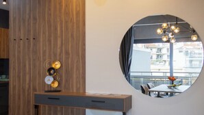 Un comedor moderno con un panel de madera decorativo, un espejo redondo y vistas al exterior.