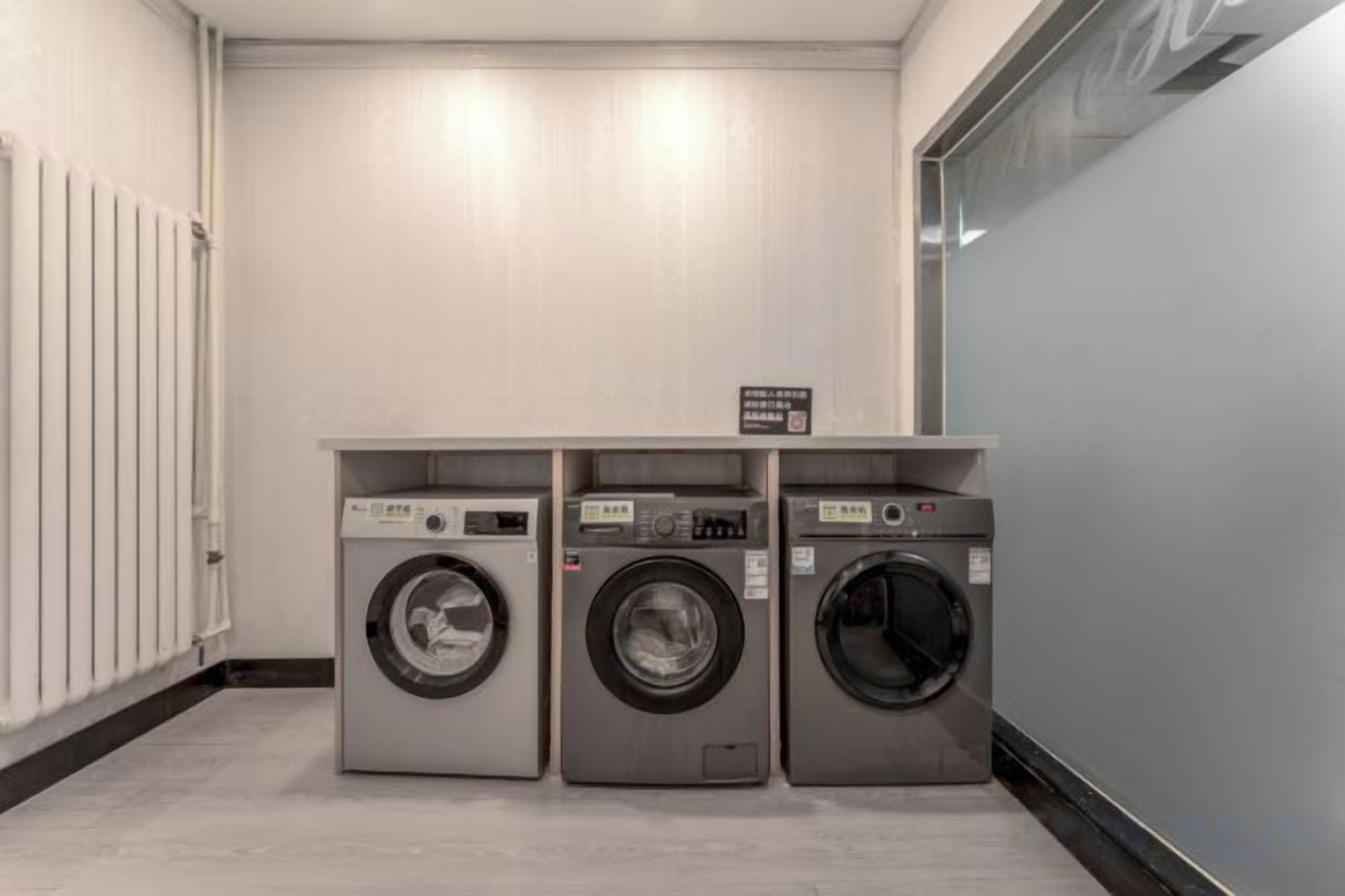 A laundry facility with three stacked washing machines and a sign indicating the location.