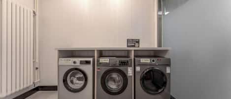 A laundry facility with three stacked washing machines and a sign indicating the location.