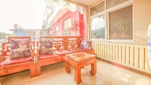 A room with a sofa set, a wooden table, and a window with a view. - Huayi Hotel(Tianjin Dongli Development Zone National Convention and Exhibition Center Store) (Tianjin)
