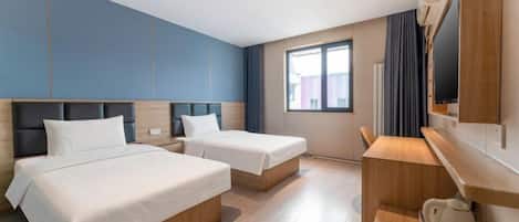 A hotel room with two beds, a desk, and a television.