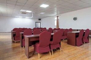 A conference room with multiple tables and chairs, a wooden floor, and a white ceiling with recessed lighting. - UP Huayi Haosleep Hotel (Tianjin Dongli Development Zone) (Tianjin)