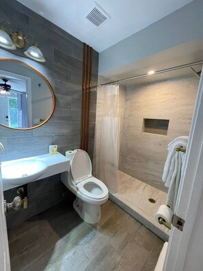 Un bagno moderno con lavandino, water e doccia bianchi.