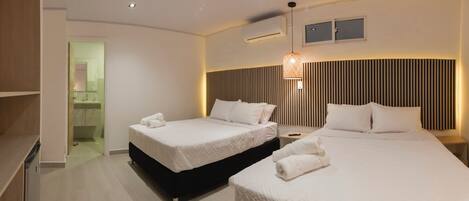 A hotel room with two beds, a bathroom, and a small window.