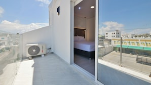 A balcony with a bed, a window, and a view of a cityscape. - Hotel Blu Sai (San Andres)