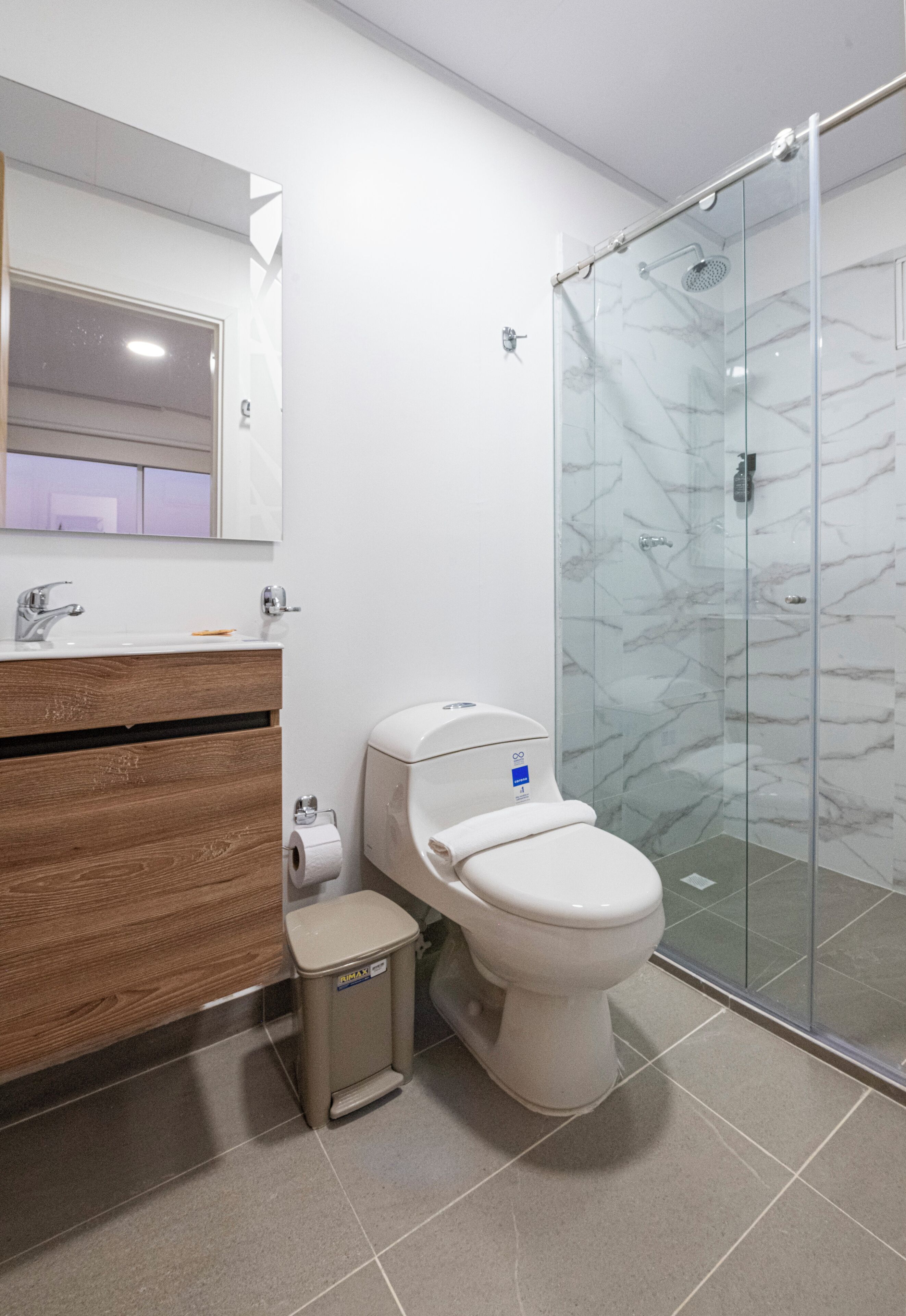 Une salle de bain moderne avec une douche à parois de verre, un meuble-lavabo en bois et des toilettes.