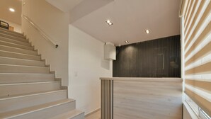 A modern staircase with a handrail, a wooden reception desk, and a dark wall with vertical lines. - Hotel Blu Sai (San Andres)