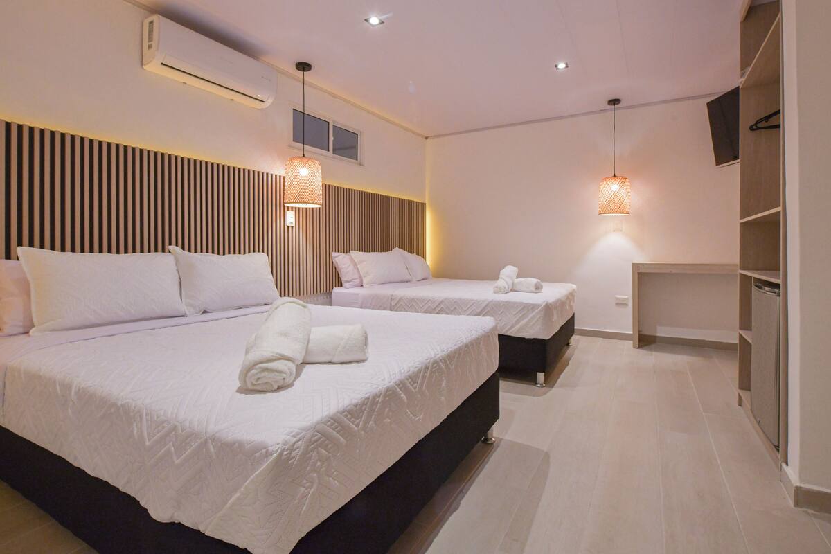 A hotel room with two beds, a wardrobe, and a TV.