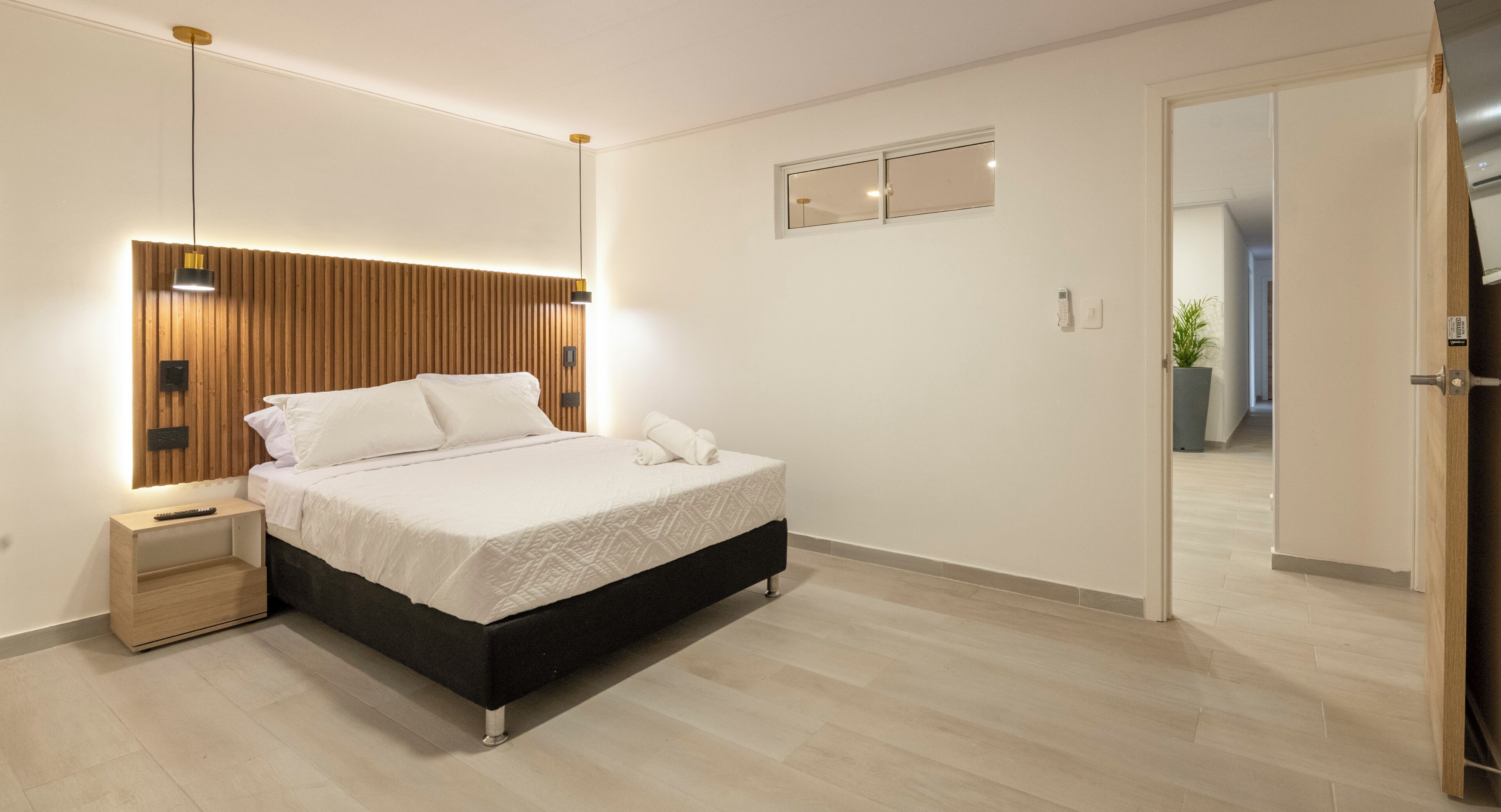 A modern bedroom with a bed, bedside table, and a mirror.