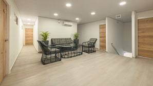 A modern room with a sofa, two chairs, a glass coffee table, and two potted plants. - Hotel Blu Sai (San Andres)