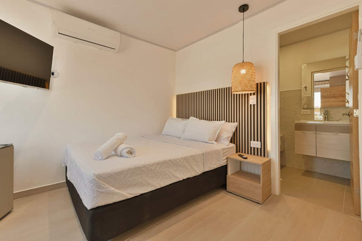 A modern bedroom with a bed, bedside table, and a hanging light fixture.