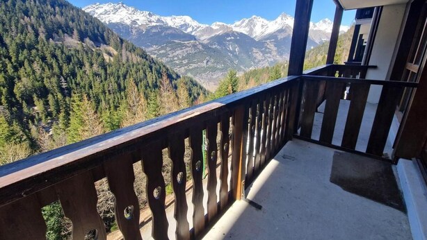 En balkon med udsigt til sneklædte bjerge og tæt skov.