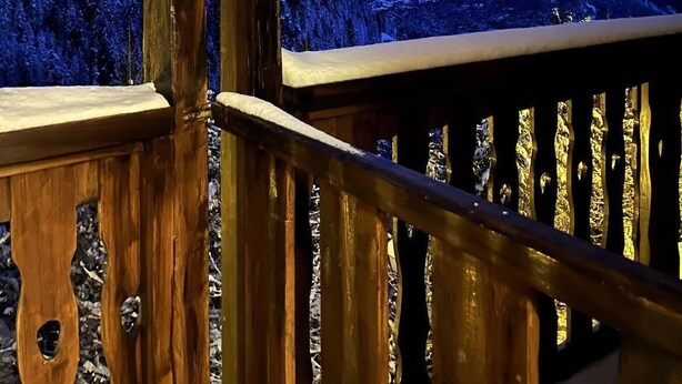 Uma varanda de madeira com vista para montanhas cobertas de neve.