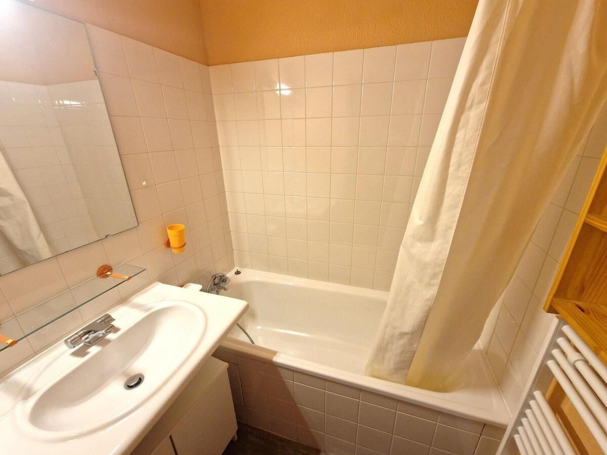 Un baño con lavamanos blanco, espejo y bañera.