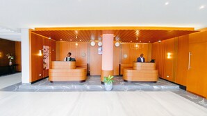 Een receptiegedeelte met twee houten balies, een grote centrale pilaar en een potplant.