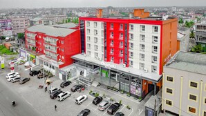 Een hotel met een gevel in rood en wit, meerdere verdiepingen en een commercieel gedeelte op de begane grond met winkels.
