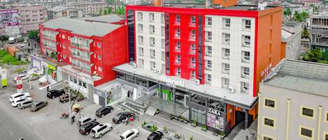 A hotel with a red and white facade, multiple floors, and a ground-level commercial area with shops.