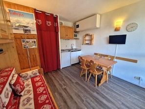A compact kitchen with wooden cabinets, a sink, and a dining area with a wooden table and chairs.