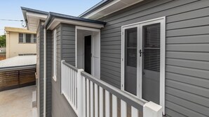 A residential building with a grey exterior, white window frames, and a small balcony with a white railing. - Botanic Breeze on Lindsay! (East Toowoomba)