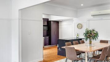 A modern kitchen with white walls, dark cabinets, and a wooden dining table with chairs.