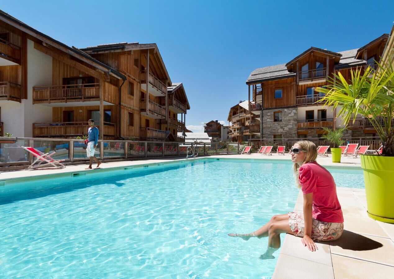 Ein Poolbereich mit Holzbauten, Liegestühlen und einem klaren, blauen Pool.