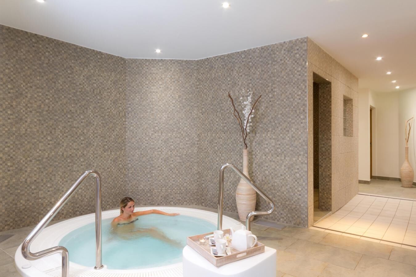 Un espace détente avec un jacuzzi, un vase décoratif et un plateau contenant des tasses et une théière.