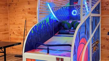 Un jeu d’arcade de basket-ball avec un intérieur en bois et une table située à gauche.