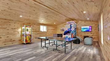Une pièce avec une table de ping-pong, une machine à pinces et un téléviseur fixé au mur.