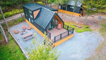 A cabin with a deck, outdoor seating, and a fire pit.